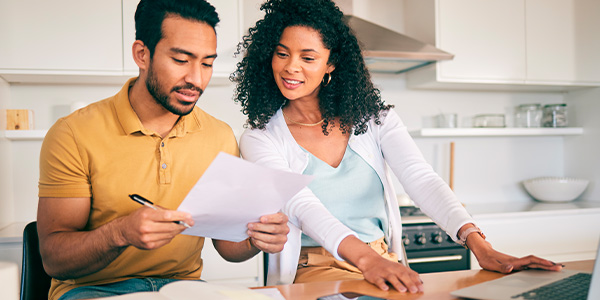 Casal de homem e mulher em uma cozinha verificando documentos